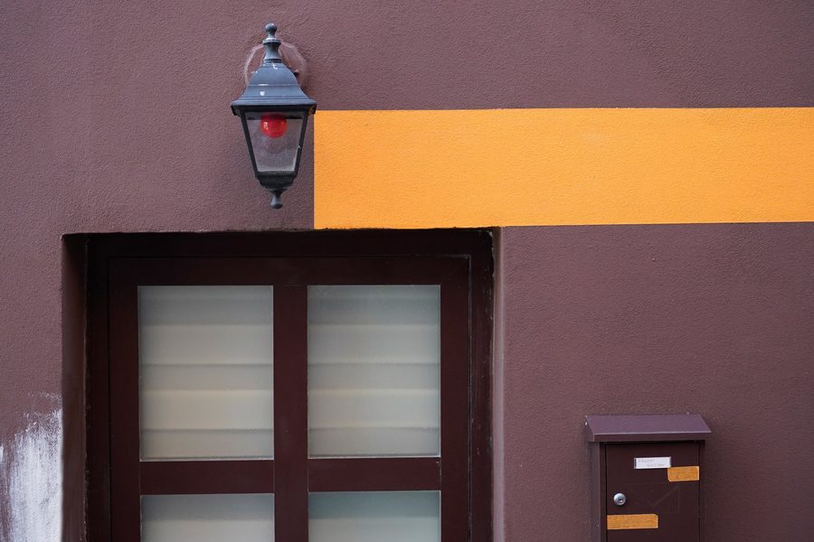 Minimal architectural wall with a yellow horizontal line, door and mailbox