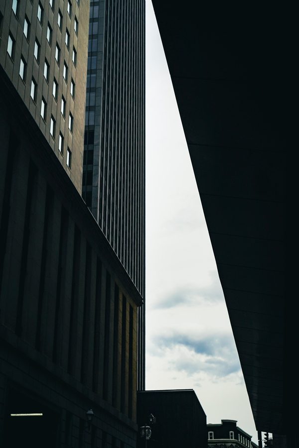 Dark urban architectural passage with tall buildings and a narrow bright sky opening