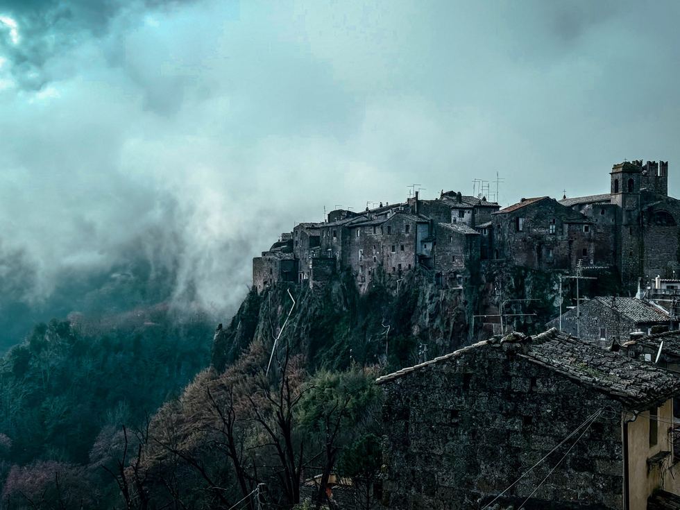 Stone village on a cliff wrapped in blue fog