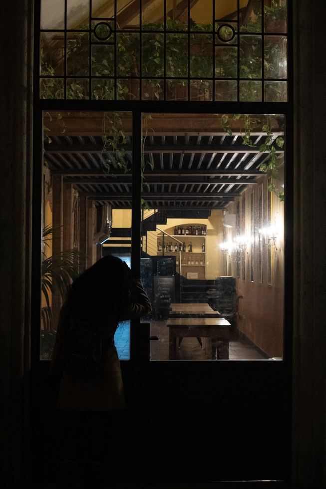 Dark human silhouette near a lit glass doorway at night