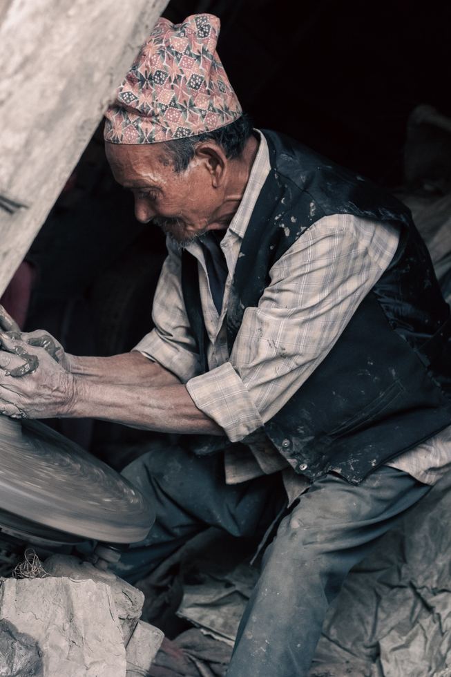 Craftsman shaping clay in a dim interior