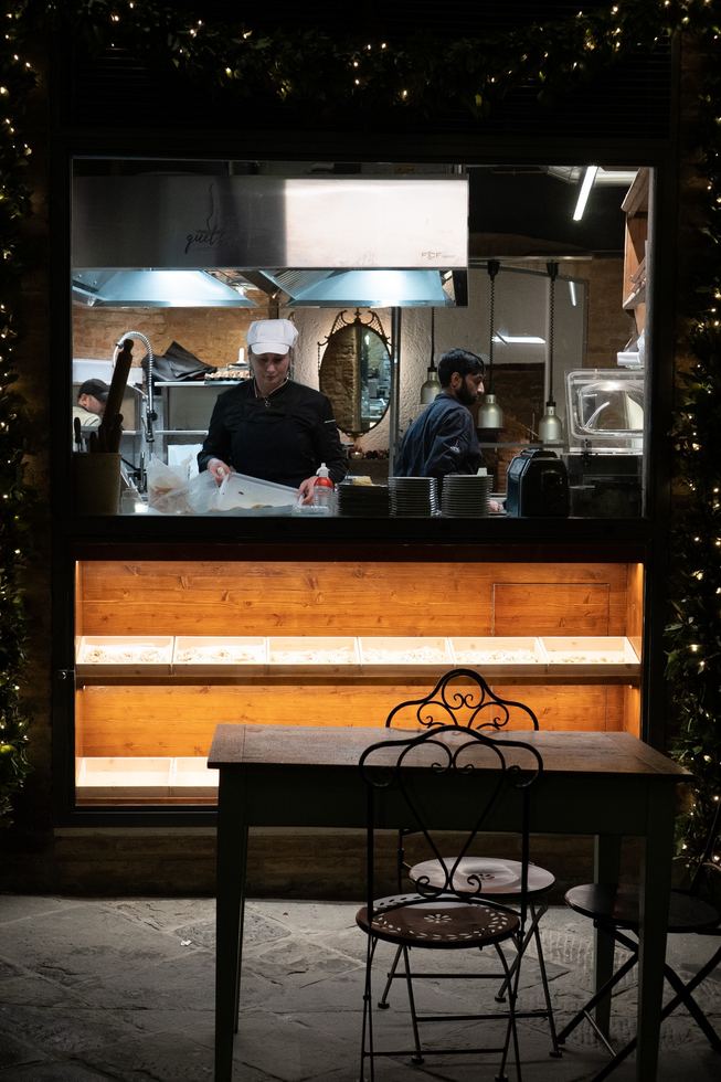 Kitchen workers framed by a lit window at night