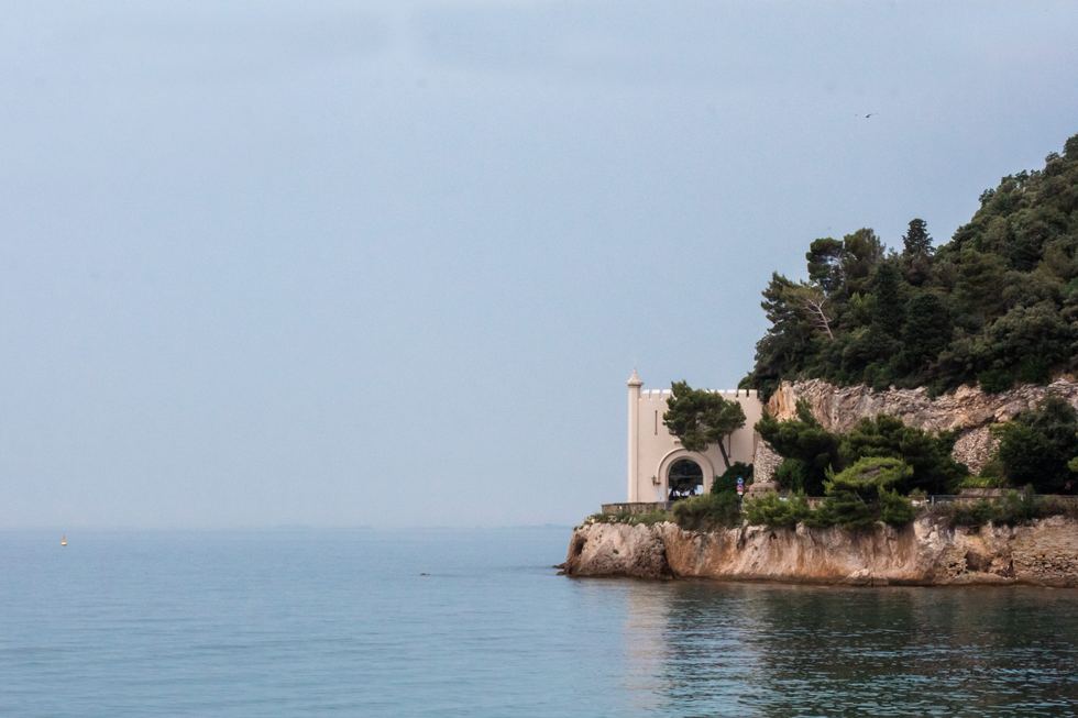 Quiet sea and stone coastal structure under a pale sky